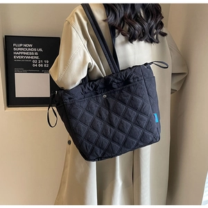 Close-up of quilted black tote bag showing detailed rhombus stitching and fabric texture