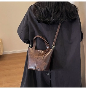 Détail d'un sac seau vintage en cuir PU marron avec breloque étoile sur trench-coat noir