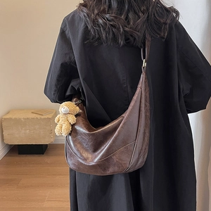 Brown faux leather crescent hobo bag with plush bear charm and spacious retro design