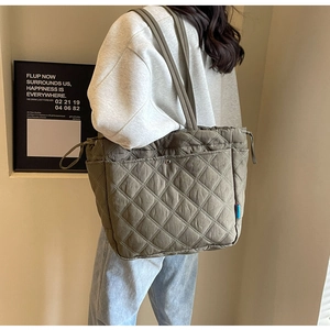 Close-up of quilted grey-brown tote bag with drawstring side and metal pocket detail