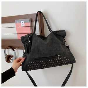 Ampia borsa tote grigio scuro con borchie e frange su un appendino in legno