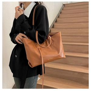 Brown crocodile pattern tote bag shown on shoulder in a professional office setting