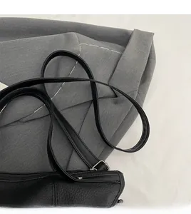 Detail of adjustable leather shoulder strap and silver metal buckle on black tote bag