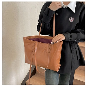 Detail of caramel brown tote bag with crocodile texture and purple lining interior