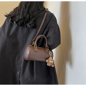 Detail of dark brown leather Boston bag with embossed logo and cute plush charm detail