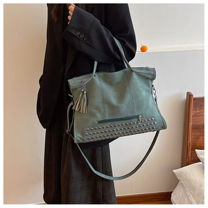 Dettaglio della borsa tote verde con rivetti metallici e nappine in pelle opaca