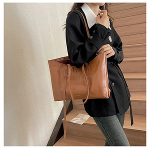 Brown leather tote bag featuring Fashion Bags text shown on a model in a casual setting