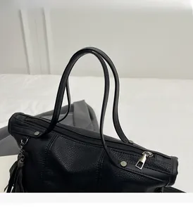 Detail of black tote bag with lychee texture leather, tassels, and silver rivets