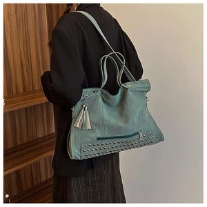 Dettaglio della borsa tote turchese con rivetti metallici vintage e nappina laterale