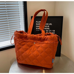 Détail du sac cabas matelassé orange avec poche à bouton pression et cordon de serrage
