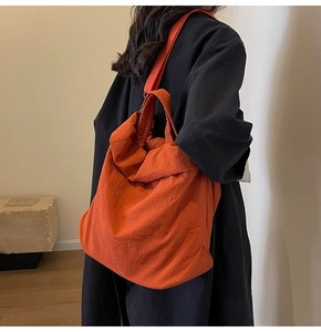 Orangefarbene Nylon-Einkaufstasche mit Plissee-Struktur an der Schulter zum Mantel
