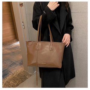 Detailed view of brown crocodile pattern tote bag shown over shoulder for size scale