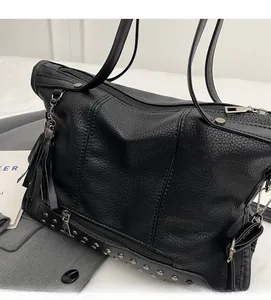 Detail of black lychee grain tote bag showing silver rivet studs and leather tassel charm