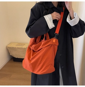 Detailansicht der großen orangefarbenen Nylon-Umhängetasche mit breitem Gurt und Schnallen
