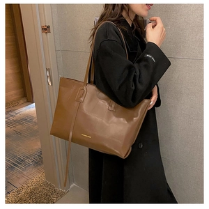 Detail of dark brown tote bag on model's shoulder showing leather texture and fashion bags text