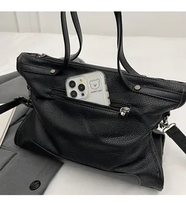 Detail of black litchi grain leather tote with silver zipper pocket and phone compartment
