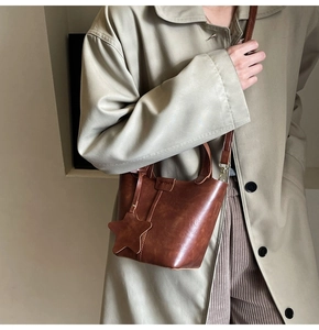 Sac seau vintage en cuir marron avec breloque étoile porté avec un trench olive