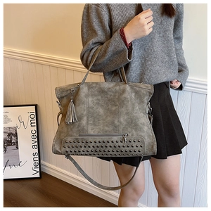 Dettaglio borsa tote vintage con borchie metalliche, nappe in pelle e tracolla