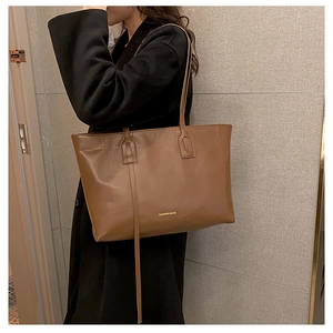 Brown vintage faux leather tote bag with gold lettering shown on a model's shoulder