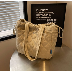 Close-up of quilted beige tote bag showing diamond stitching and drawstring detail