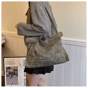Dettaglio della borsa tote in pelle scamosciata grigio-verde con rivetti e nappa alla moda