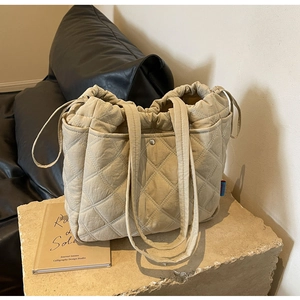 Detail of beige quilted tote bag with side drawstrings and large storage pockets