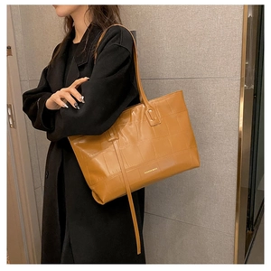 Detail shot of caramel brown tote bag with crocodile embossed texture and fashion logo