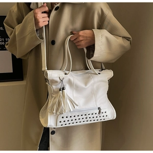 Detailed view of white lychee texture tote bag featuring silver studs and long tassels