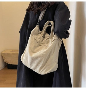 Detail der hellbeigen Nylon-Tragetasche mit breitem Schultergurt und Metallhaken