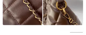Detailed close-up of brown quilted leather texture and gold metal chain strap on a tote bag