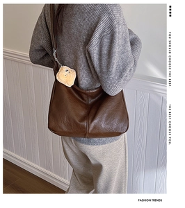 Close-up of a brown leather tote bag with a cute plush bear charm for a vintage look
