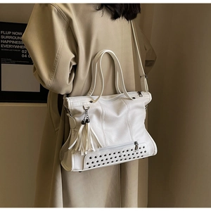 Detail view of white tote bag with lychee texture, metal rivets and tassel ornament