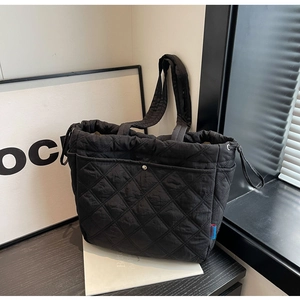 Gros plan du sac fourre-tout noir matelassé avec cordon de serrage et poche à bouton