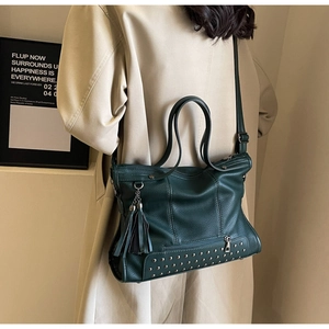 Detail of dark green pebbled leather tote with silver studs and tassel charm