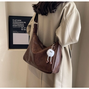 Detail of soft dark brown leather crossbody bag with a cute white plush charm on model