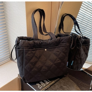 Close-up of black quilted tote bag featuring rhombus stitching and side drawstrings