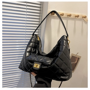 Detail of black quilted leather tote with large diamond pattern and golden twist lock