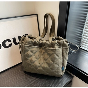 Detail of olive green quilted tote bag showing rhombus stitching and drawstring closure