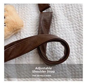Detail of adjustable dark brown leather strap with silver buckle on plush tote bag
