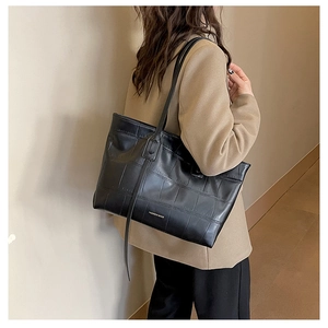 Detail of black crocodile pattern leather tote bag with elegant thin shoulder straps