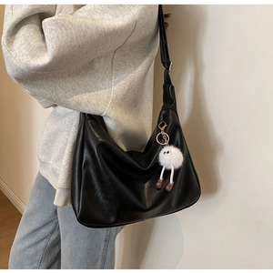 Detail of soft black hobo bag with zip closure and plush white charm accessory