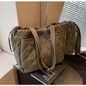 Detail of olive green quilted tote bag with diamond stitching and side pocket