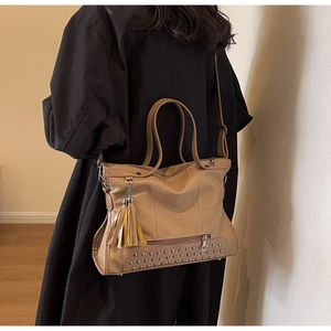 Close-up of khaki tote bag with metal rivets, leather tassels and litchi texture