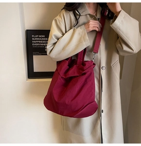 Detailaufnahme der weinroten Nylontasche mit strukturierter Oberfläche und Tragegurt