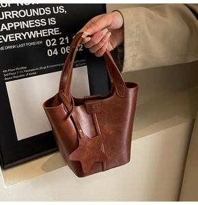Vue détaillée du sac seau en cuir marron avec pendentif étoile porté par un mannequin