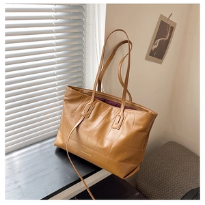 Detail of brown crocodile pattern tote bag with long straps and gold zipper closure