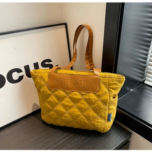 Detail of ginger yellow quilted tote bag with brown PU straps and branded leather patch