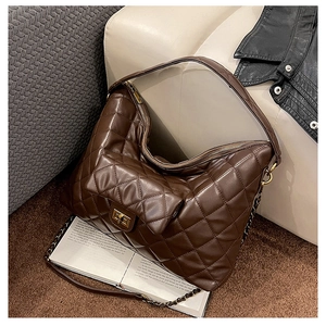 Detailed close-up of brown quilted leather tote with gold twist lock on a soft sofa