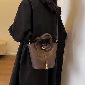 Deep brown leather bucket bag with top handles, gold hardware and smiley charm