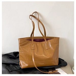 Close-up of brown tote bag with crocodile texture, fashion logo and slim straps
